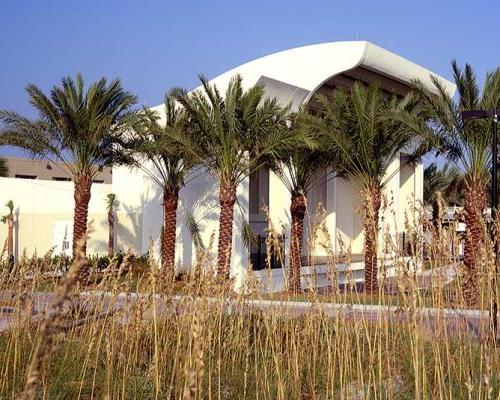 Exterior photo of Sea Walk Pavilion. Palm trees and tall grass obscure the view of the building.